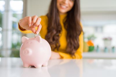 Kvinne som legger på mynt på en sparegris